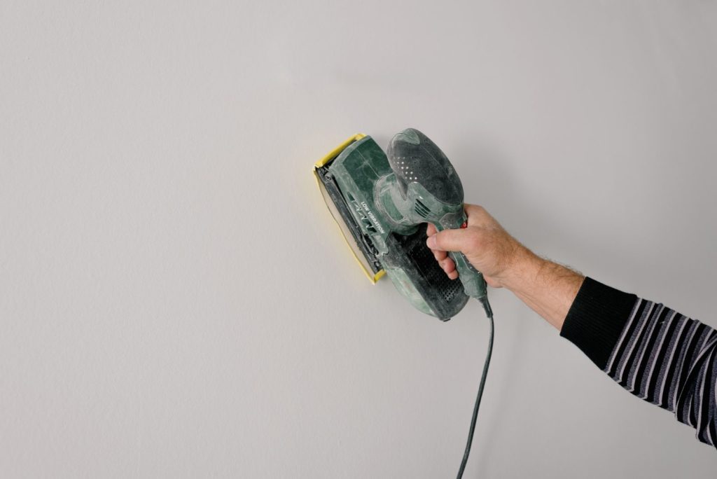 Sanding a plastered wall with an electric sander