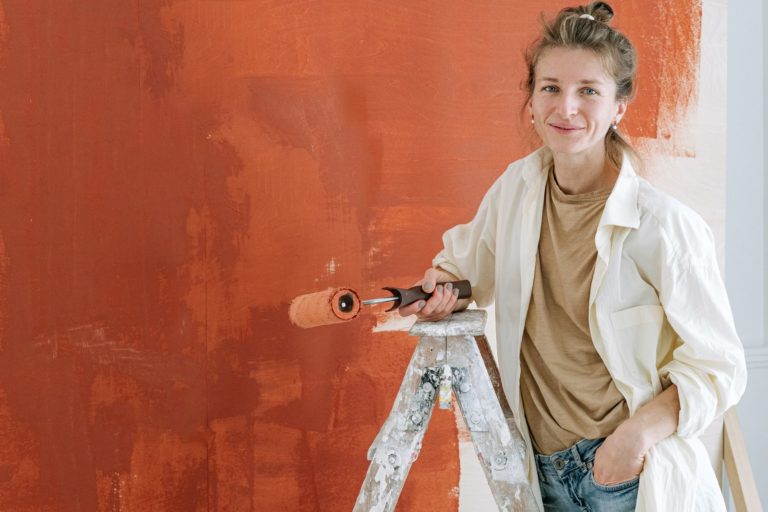 Smiling painter with a roller and a terracotta wall