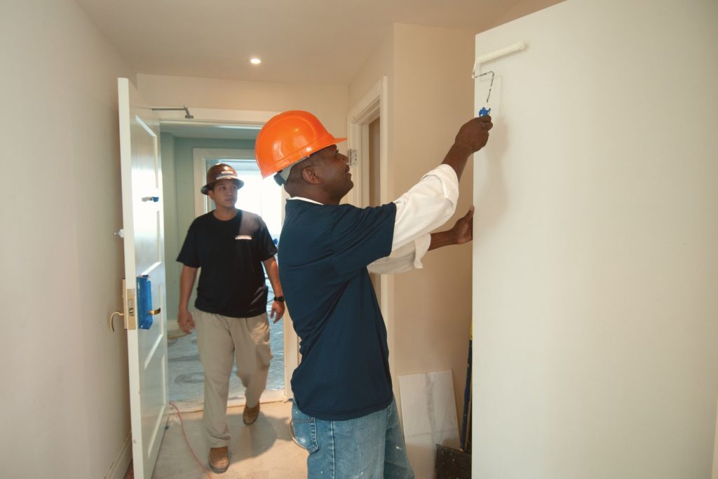 Two workers painting an interior hallway