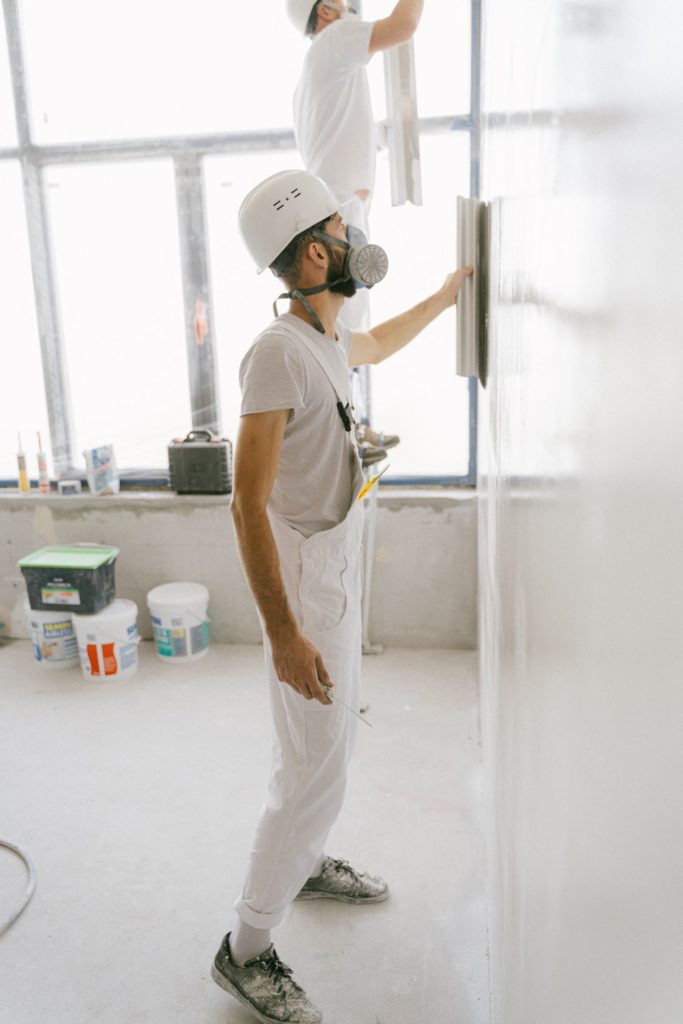 Plasterer with a mask working on a wall