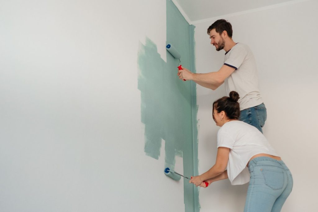 Couple painting a wall sage green